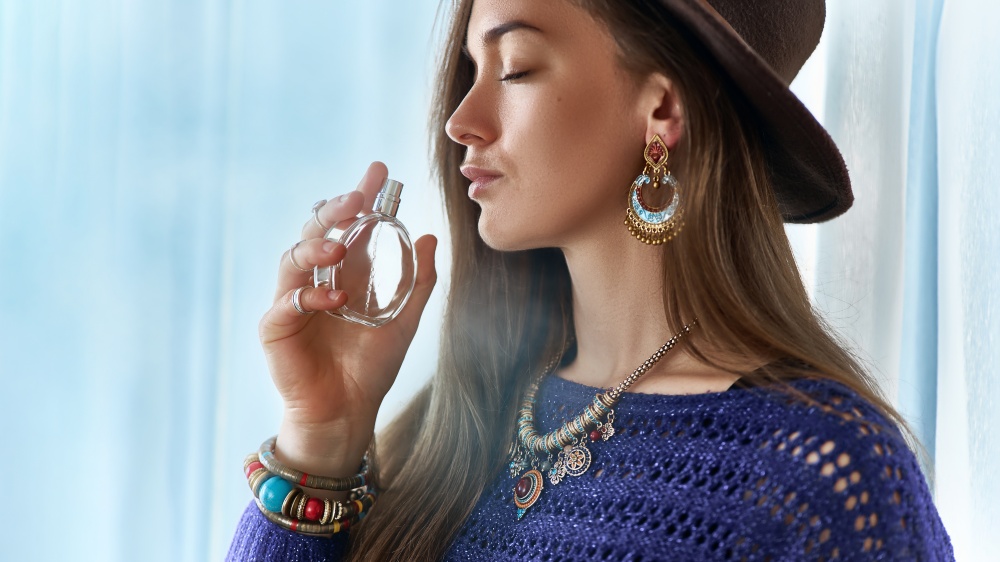 O femeie adulmeca parfum dintr-o sticluta tinand ochii inchisi