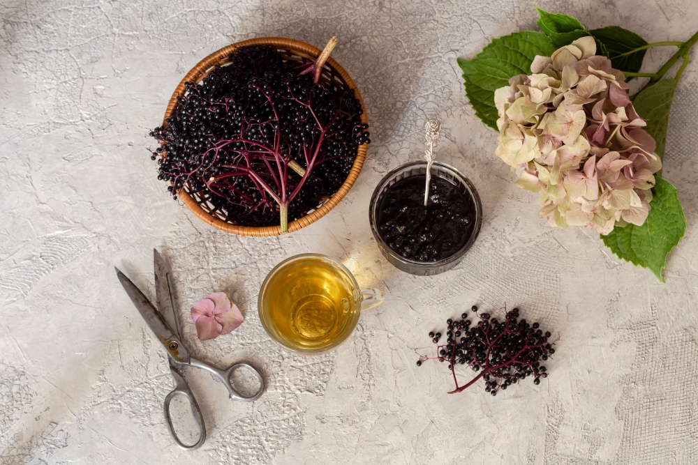 Foarfece, flori, un cos in care se afla fructe negre de soc si dulceata de soc. Pregatirea fructelor pentru dulceata.
