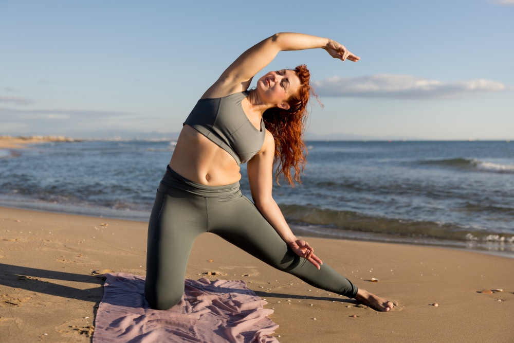 O femeie pracrica yoga pe plaja