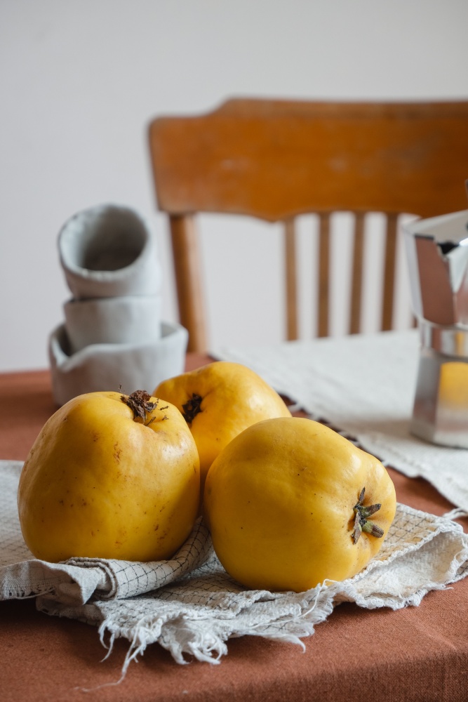 3 gutui asezate pe un servet de bucatarie, decor rustic