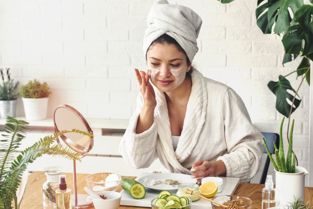O femeie tanara isi aplica pe fata crema naturala cu SPF facuta in casa