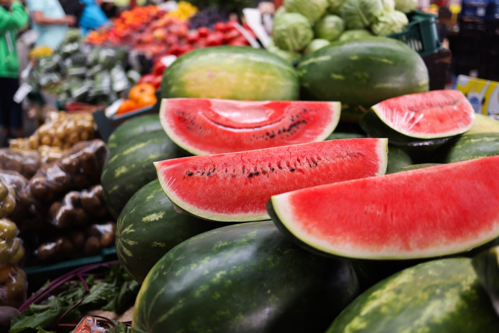 Felii de pepene rosu si fructe intregi intr-o piata