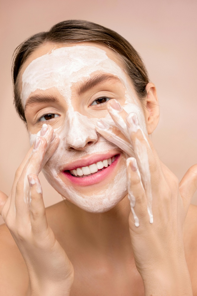 O femeie se spala pe fata, spuma de la sapun anti-aging