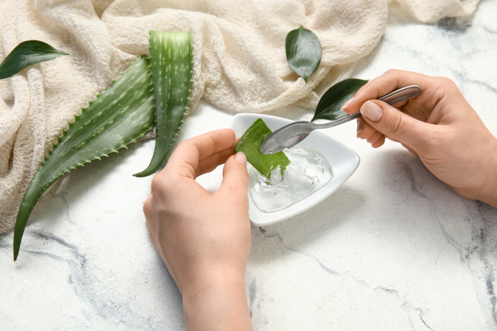 Mainile unei persoane care curata frunze de aloe vera