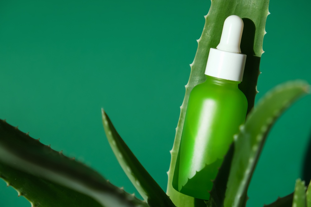 O sticluta cu gel pentru fata asezata pe o frunza de aloe vera