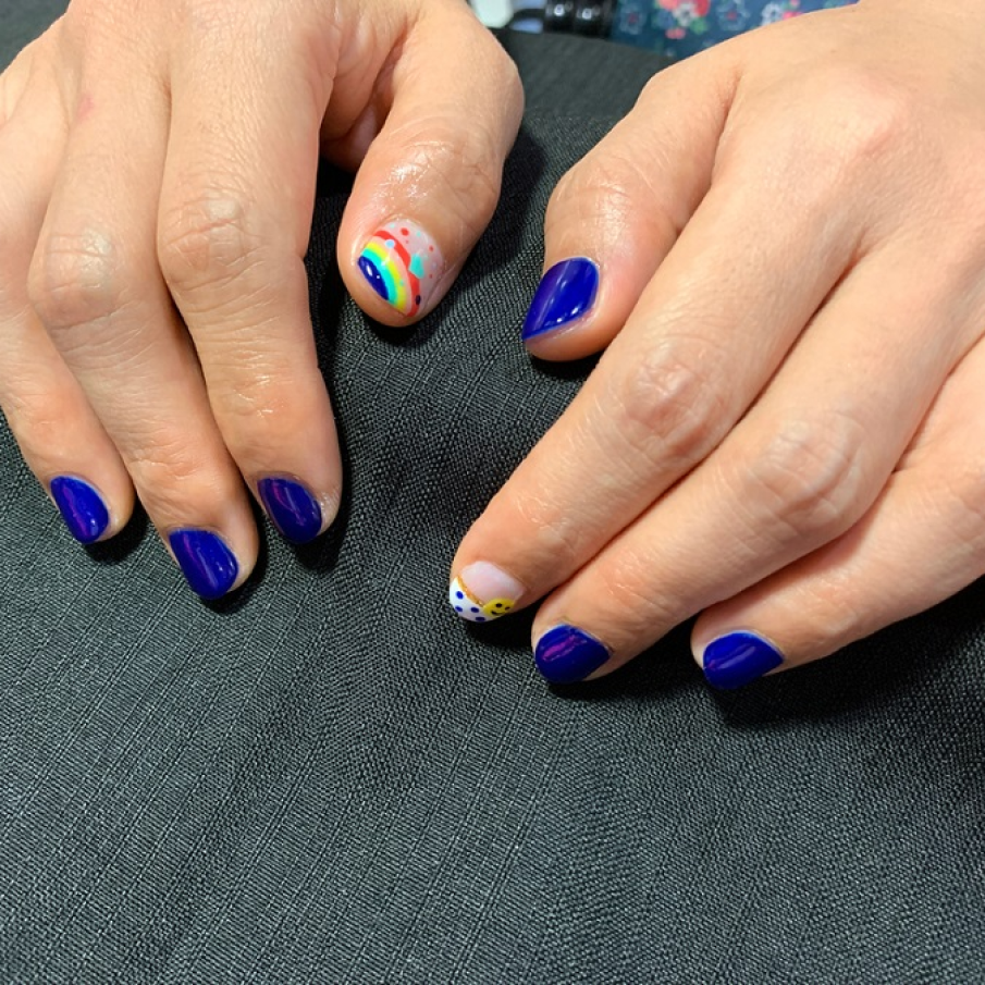 Manichiură albastru roial, cu detalii jucăușe precum curcubeu, buline și inimioare 