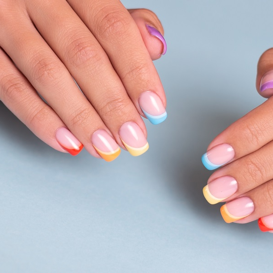 Manichiură curcubeu în stil franțuzesc, cu vârfurile unghiilor atinse de culorile curcubeului 