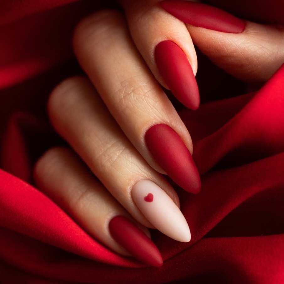 O idee de manichiură simplă, dar de efect, pe bază de ojă roșie mată. Pe unghia arătătorului, pe o bază nude, este pictată o inimioară așa că această manichiură poate fi o alegere inspirată și pentru Ziua Îndrăgostiților