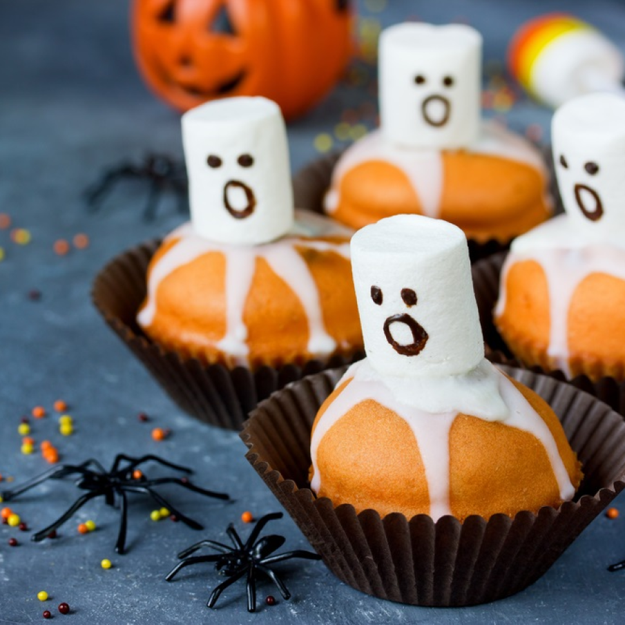 Muffins delicioase de Halloween cu dovleac, decorate cu fantome albe realizate din marshmallows și ciocolată albă 