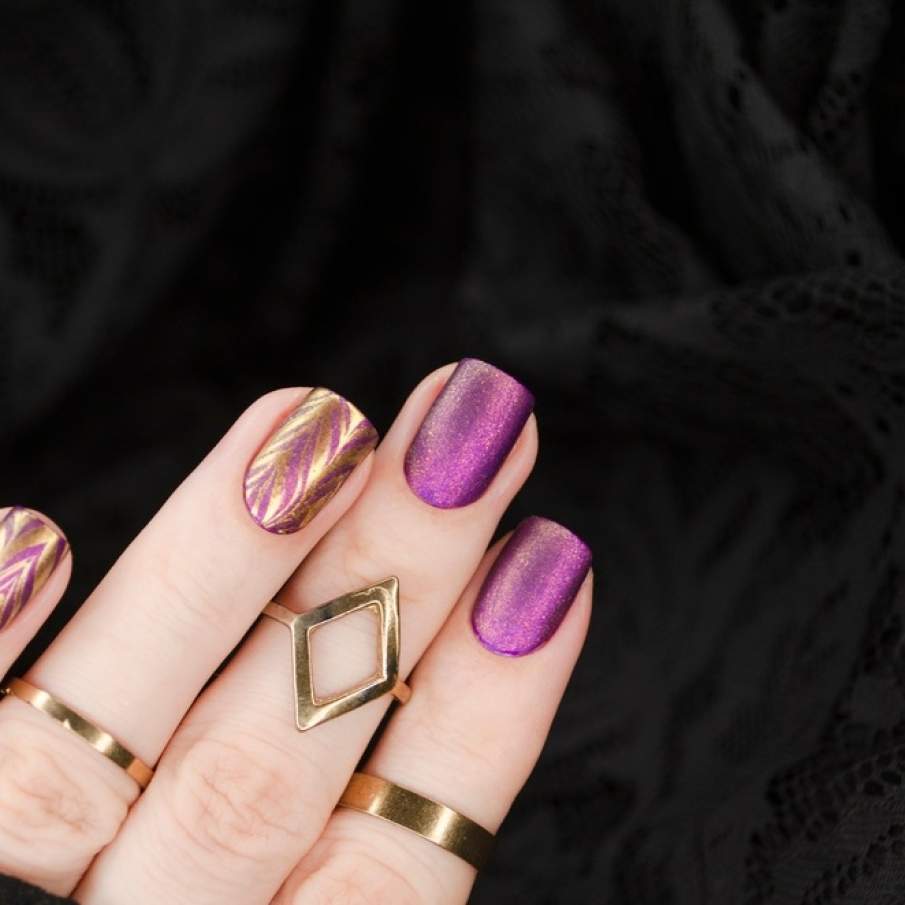 Manichiură violet glamorous, cu motive abstracte aurii și finisaje de glitter mat 