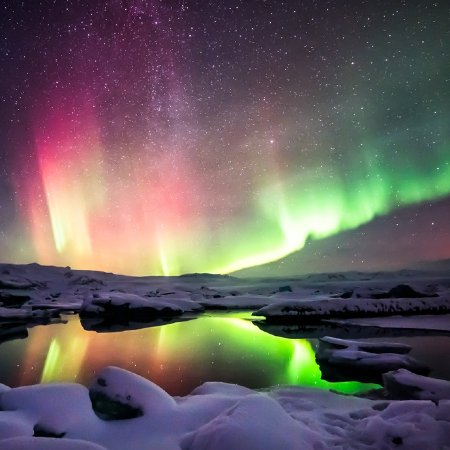 Dans de lumini verzi si rosii deasupra lagunei Jokulsarlon din Islanda