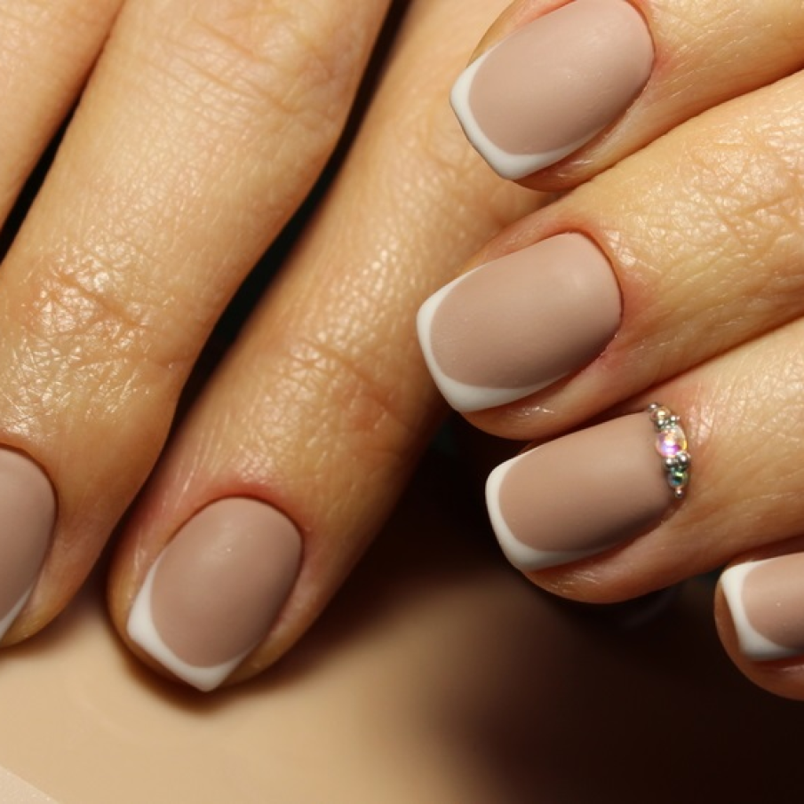 Manichiură franțuzească nude superbă, realizată pornind de la nuanțe de bej mat și alb mat. La baza arătătorului au fost aplicate cristale  Swarovski pentru un mic accent de strălucire 