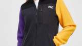 Hanorac fleece Colourwear în stil colourblock, cu o mânecă galbenă, una violet, și guler pentru protecție împotriva vântului
