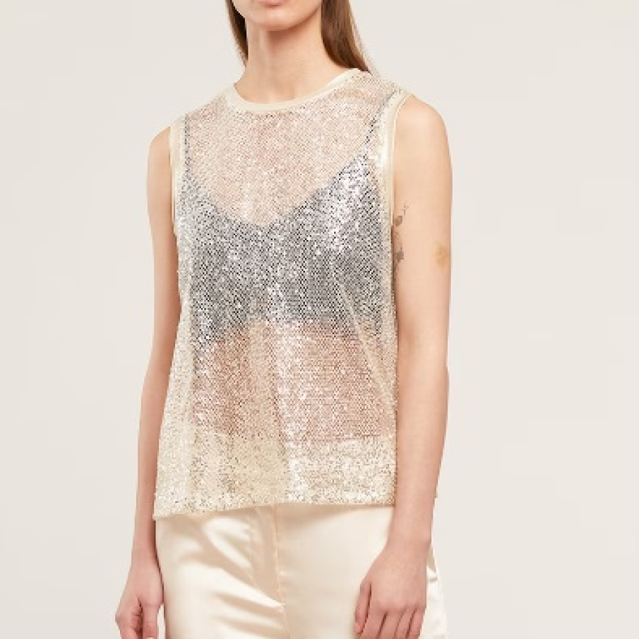 Top Motivi fără mâneci, lucios și semitransparent, decorat cu paiete. Este într-o nuanță caldă de bej deschis cu argintiu
