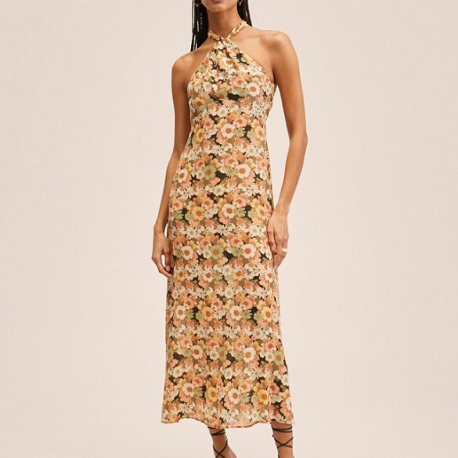 Rochie cu decolteu halter și imprimeu floral în care predomină rozul somon și cel piersică. 