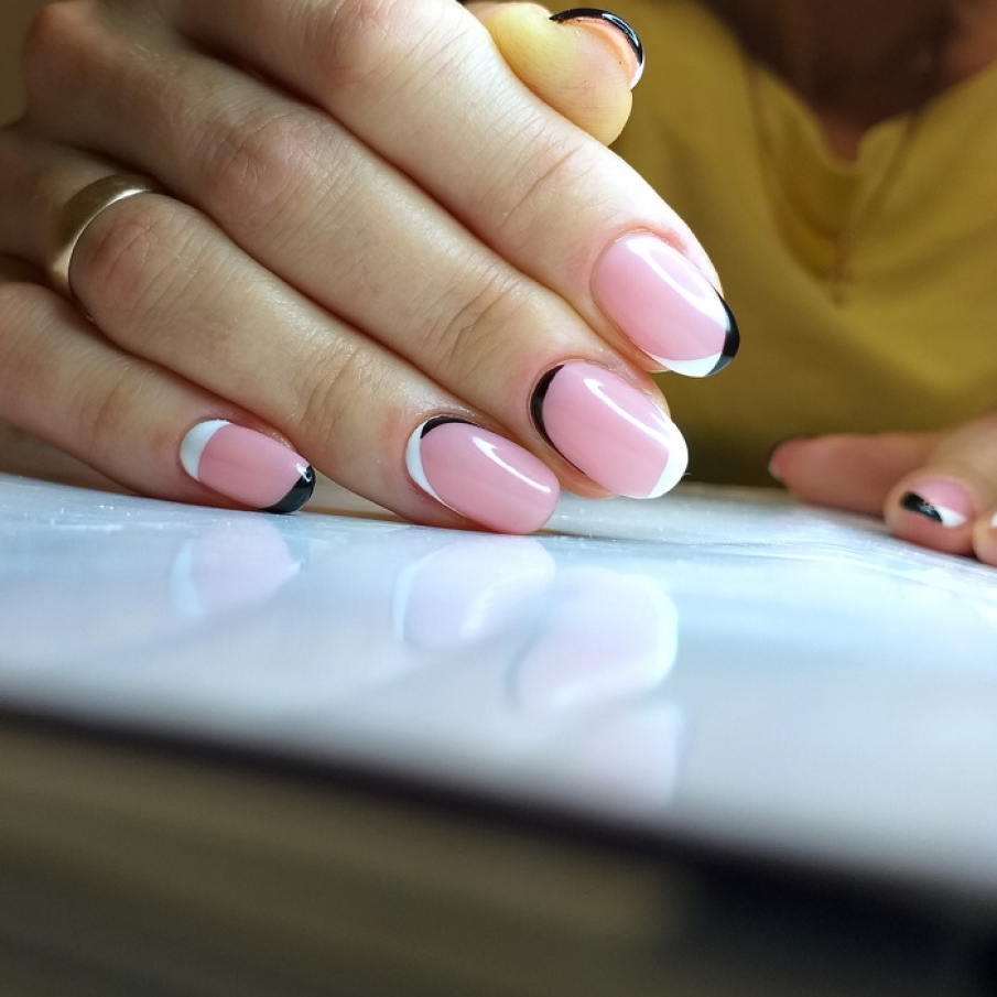 Manichiură stilată: Margini alb și negre minimaliste pe fundal de roz fondant 