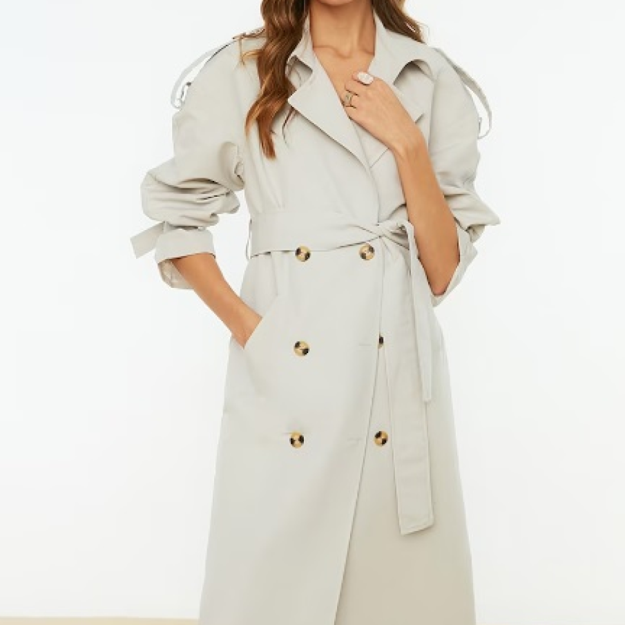 Trenci ușor supradimensionat, cu două rânduri de nasturi, într-o plăcută și deschisă nuanță de bej 