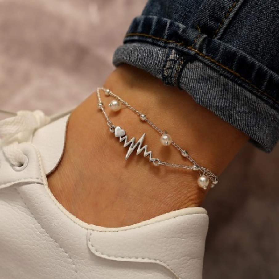 Brățară de picior modernă, dublă, din aliaj de aluminiu inoxidabil. Dispune de detalii precum perle, inima și simbolul pulsului inimii.