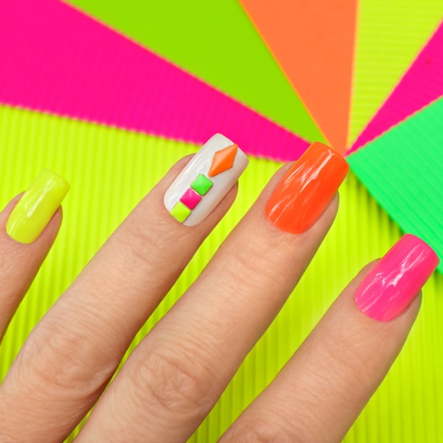 Manichiură neon multicoloră, cu ștrasuri geometrice colorate în nuanțe neon, aplicate pe unghia inelarului
