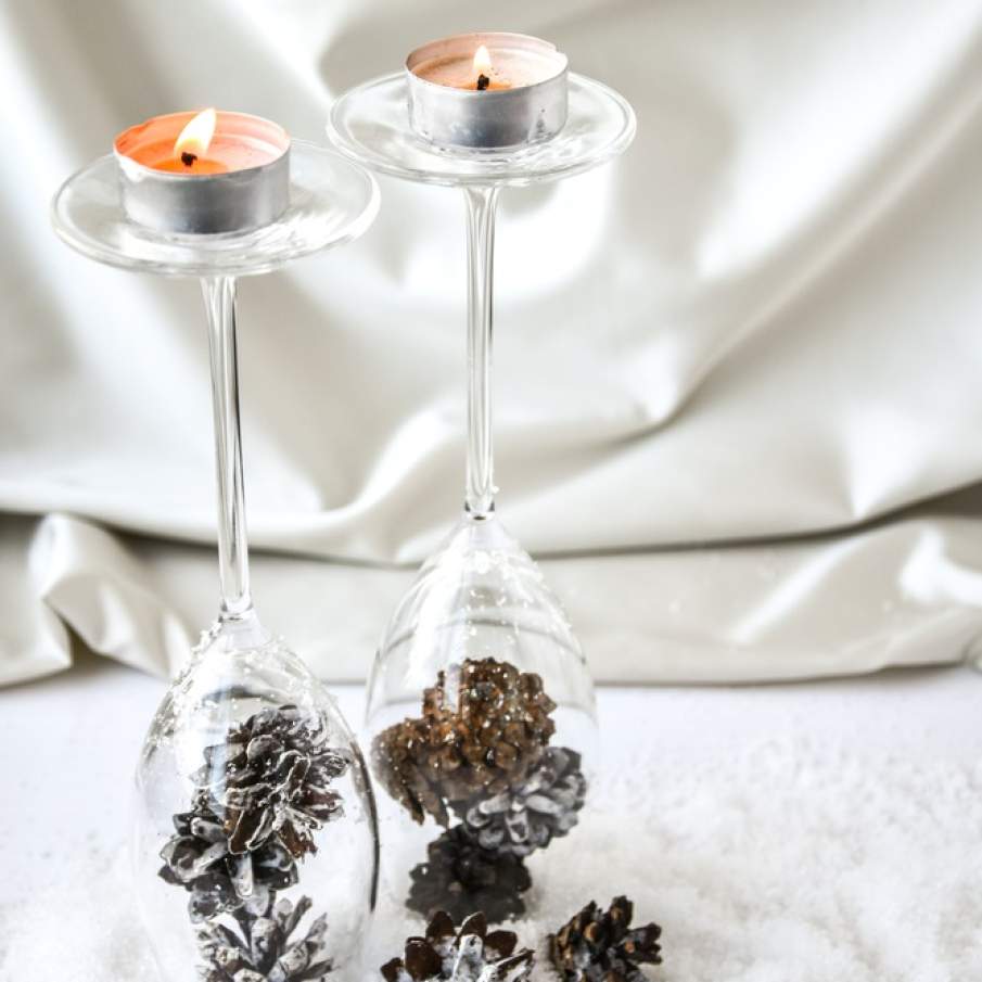 Suport decorativ de lumânări realizat din pahare de șampanie întoarse invers și umplute cu conuri de pin vopsite cu alb
