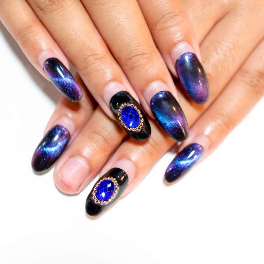 Manichiură acrilică, cu unghii în formă de migdală, cu un diamant decorativ imens aplicat pe unghia inelarului 