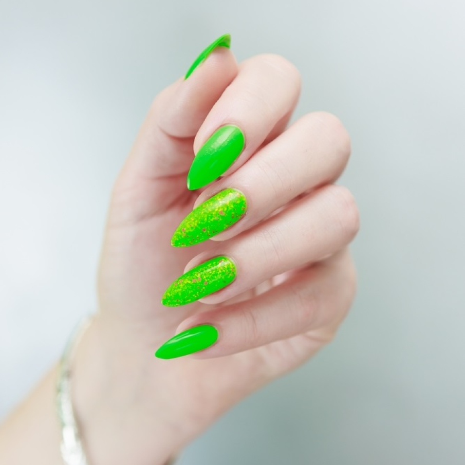 Manichiură neon în nuanță de verde praz intens, cu accente de glitter pe suprafața a două unghii