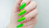 Manichiură neon în nuanță de verde praz intens, cu accente de glitter pe suprafața a două unghii