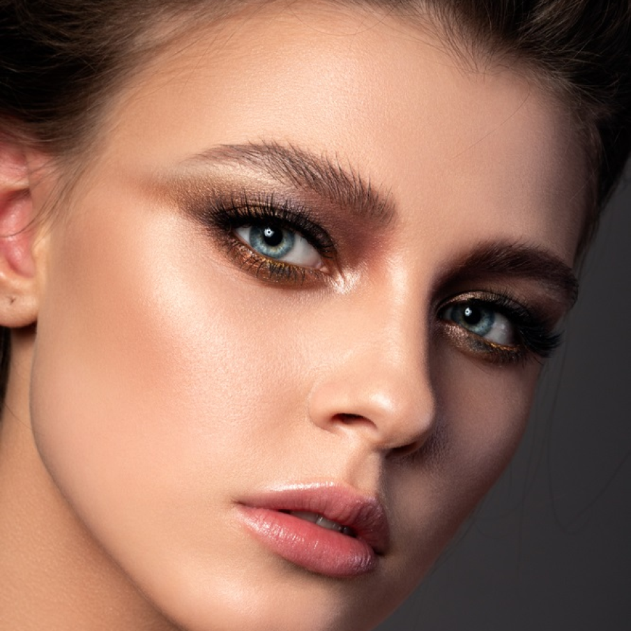 Machiaj tip smokey natural, cu sprâncenele ciufulite, buze cu gloss nude și accente de glitter auriu sub pleoapele inferioare