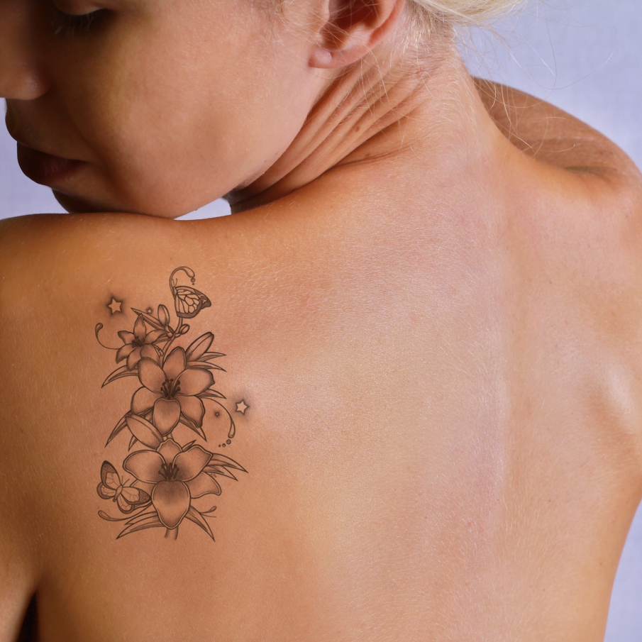 Tatuaj pe spate inspirat de natură: florile sunt puse în evidență de 2 fluturi simpatici și de 2 steluțe