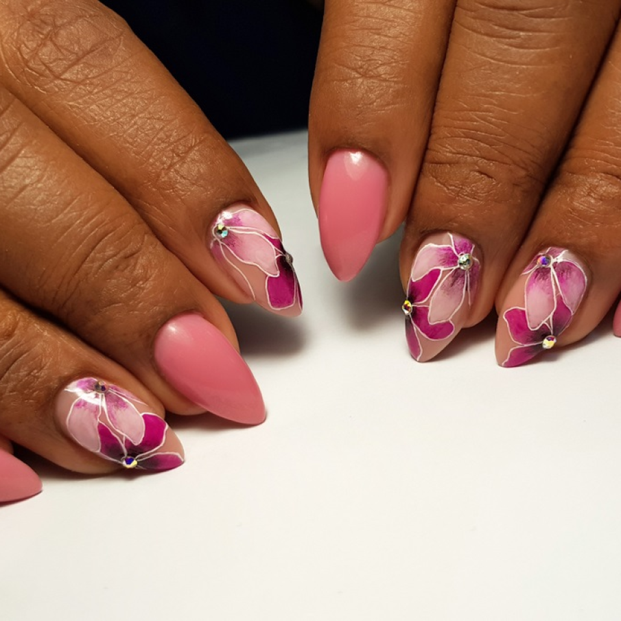 Manichiură florală roz, cu ștrasuri și flori trasate cu atenție și creativ pe unghiuțe 