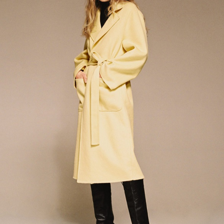 Palton Mango galben păi, din amestec de lână. Este ușor supradimensionat, dar cordonul din talie scoate din evidență silueta. 