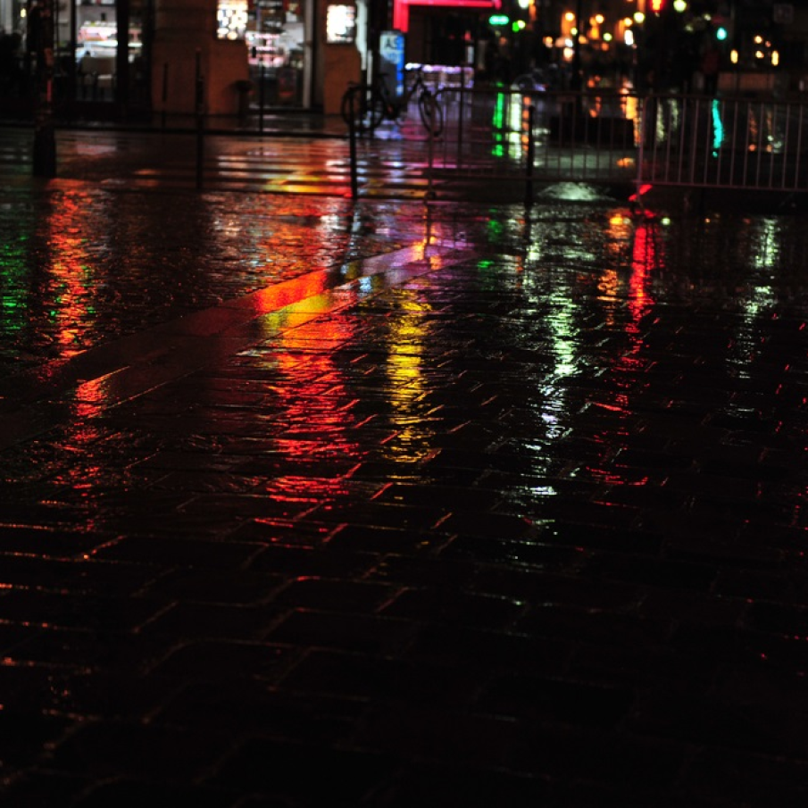 Luminile neoanelor colorate reflectandu-se pe strazile udate de ploaie ale Parisului