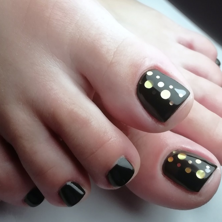 Pedichiură în nuanță de negru lăcuit, cu ștrasuri aplicate pe o singură unghie pentru un efect wow de strălucire 