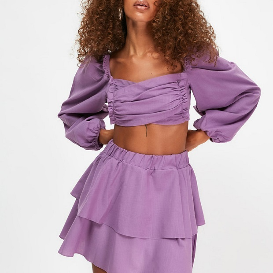 Set în nuanță de mov ametist, confecționat din bumbac. Fusta este scurtă, stratificată, iar bluza crop are mâneci bufante și bretele care dezgolesc spatele parțial.