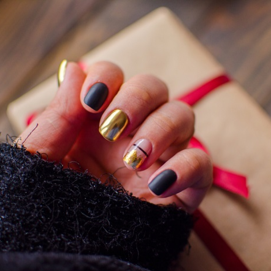 Manichiură elegantă cu auriu și negru, având spații 