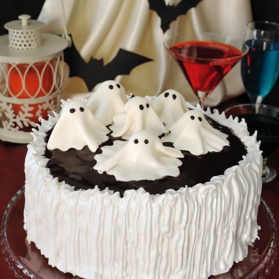 Tort delicios și impresionant de Halloween scăldat într-o baie de ciocolată și decorat cu fantome albe și sperioase din marțipan alb 