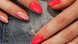 Manichiură neon în nuanță de roșu corai, cu spații negative pe unghia inelarului și a degetului mic 