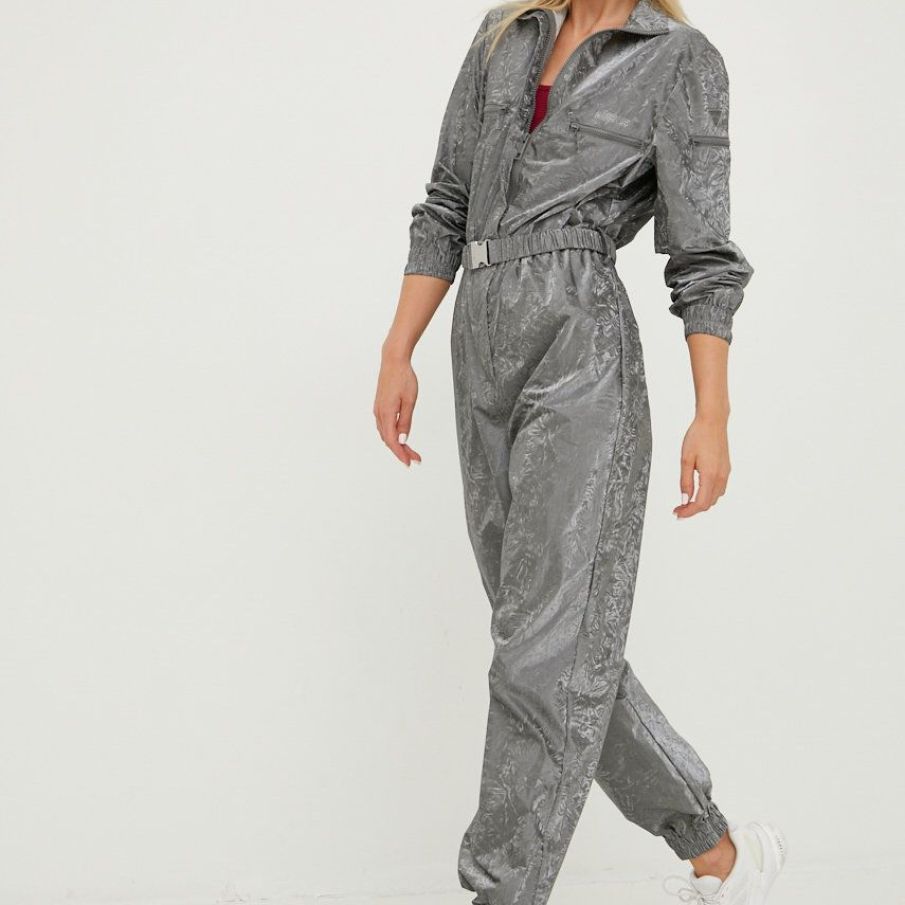 Salopetă sport casual în nuanță de gri, confecționată din textil. Dispune de bandă elastică în talie, iar piciorul pantalonului este finisat cu manșete