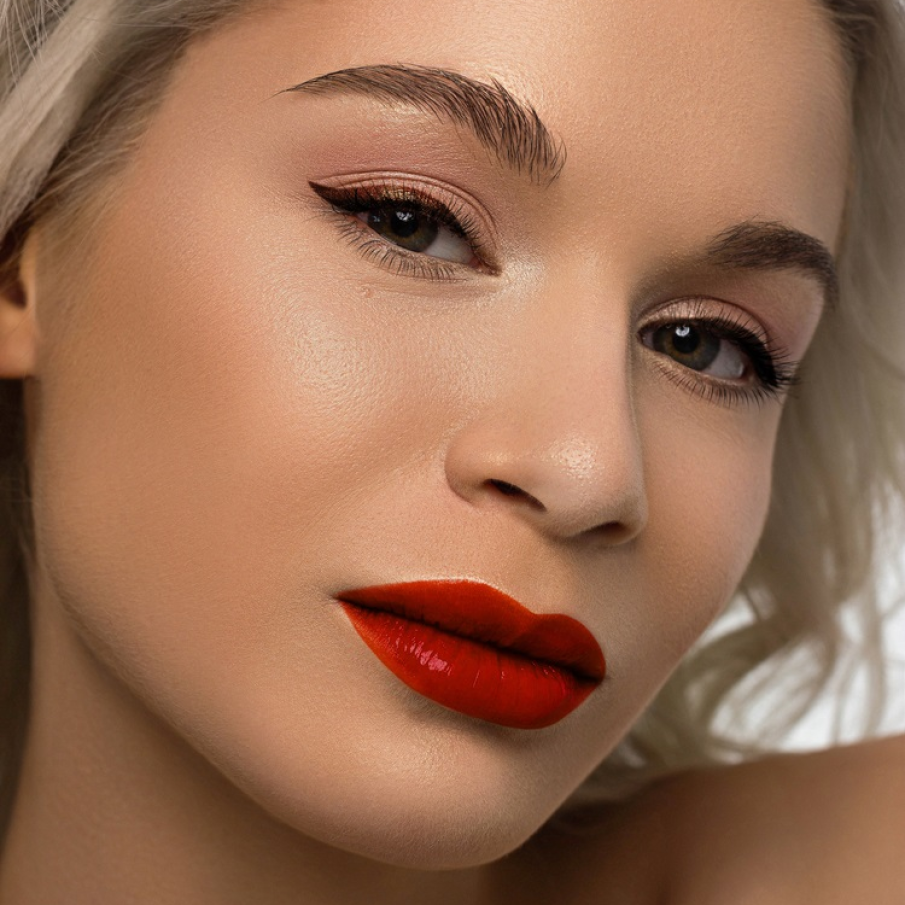 Machiaj de ”porțelan” cu tenul impecabil, cu aspect curat, buzele puse în evidență de un ruj roșu corai și ochii subliniați cu ajutorul eyelinerului maro