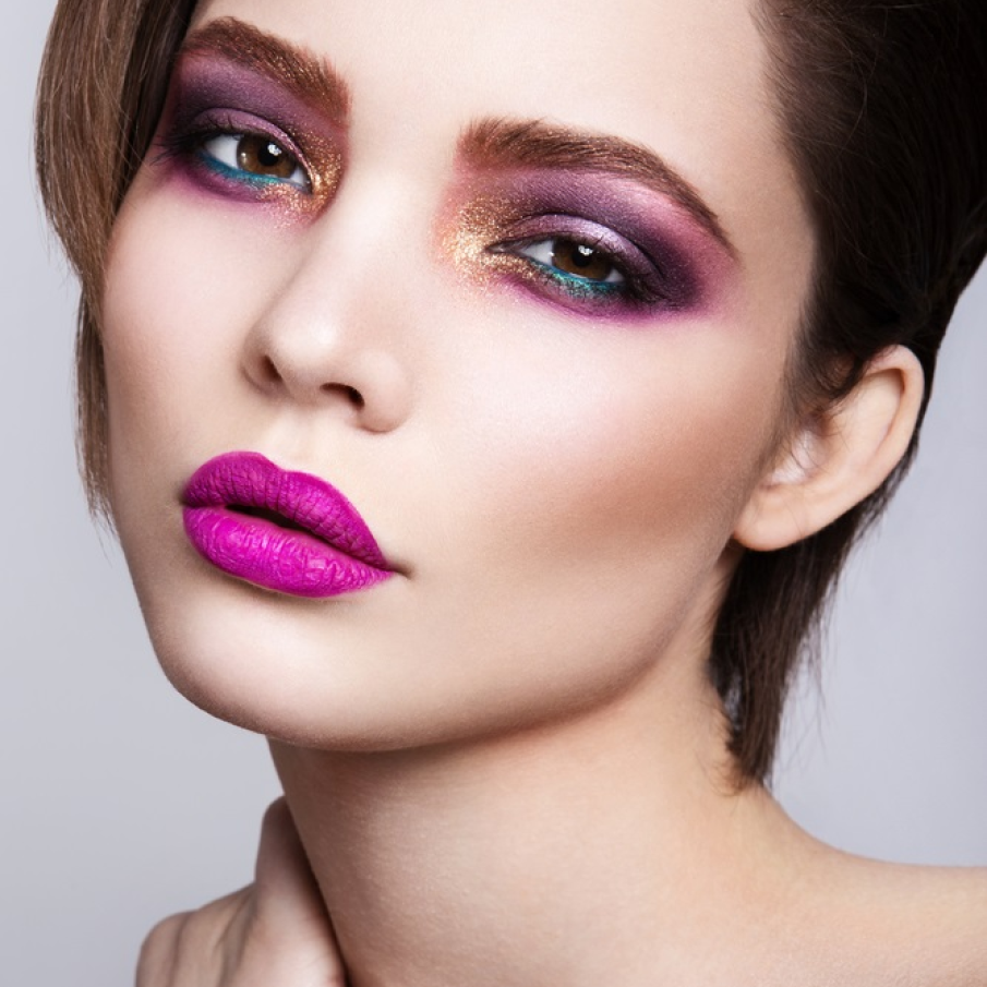 Machiaj smokey în care predomină nuanțele de mov violet. Pleoapa inferioară a fost accentuată cu dermatograf albastru, iar colțul interior al ochilor a fost evidențiat de glitterul auriu