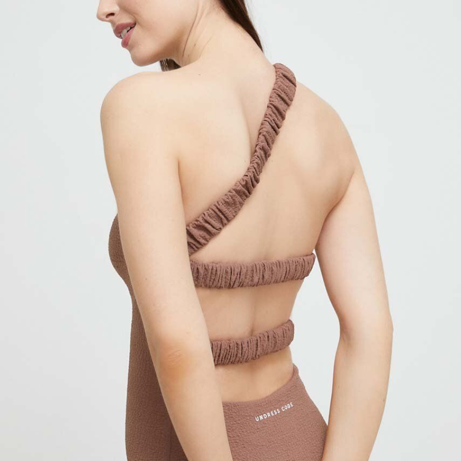 Costum de baie maro, dintr-o bucată, de la Undress Code. Este confecționat din material flexibil, confortabil. Modelul este pe un singur umăr, iar decupajele de pe spate îi conferă un aer sexy