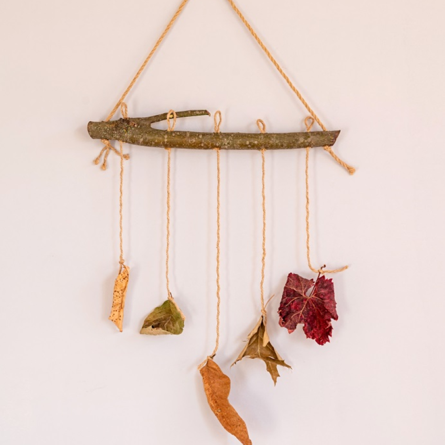 Decorațiune rustică tip ghirlandă, cu frunze uscate atârnând pe perete 