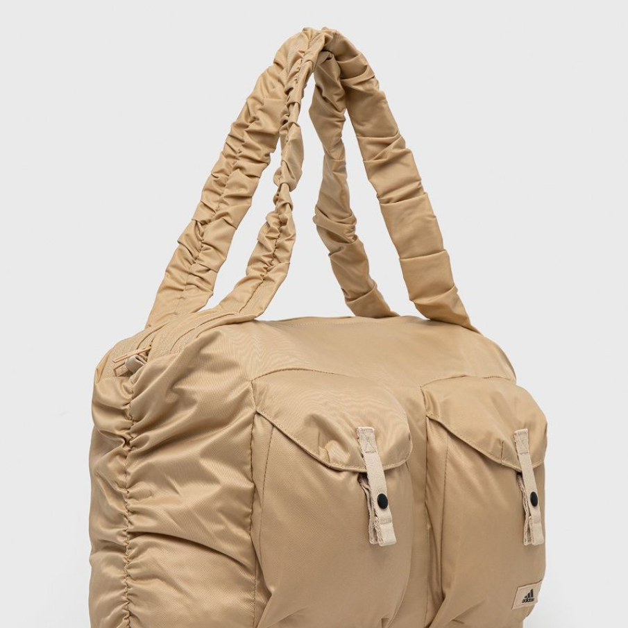 Geantă bej, cu buzunare frontale și mânere lungi, din material textil. Face parte din colecția adidas Performance