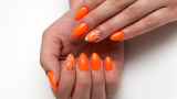 Manichiură oranj neon, cu dungi în zig zag și ștrasuri aplicate 