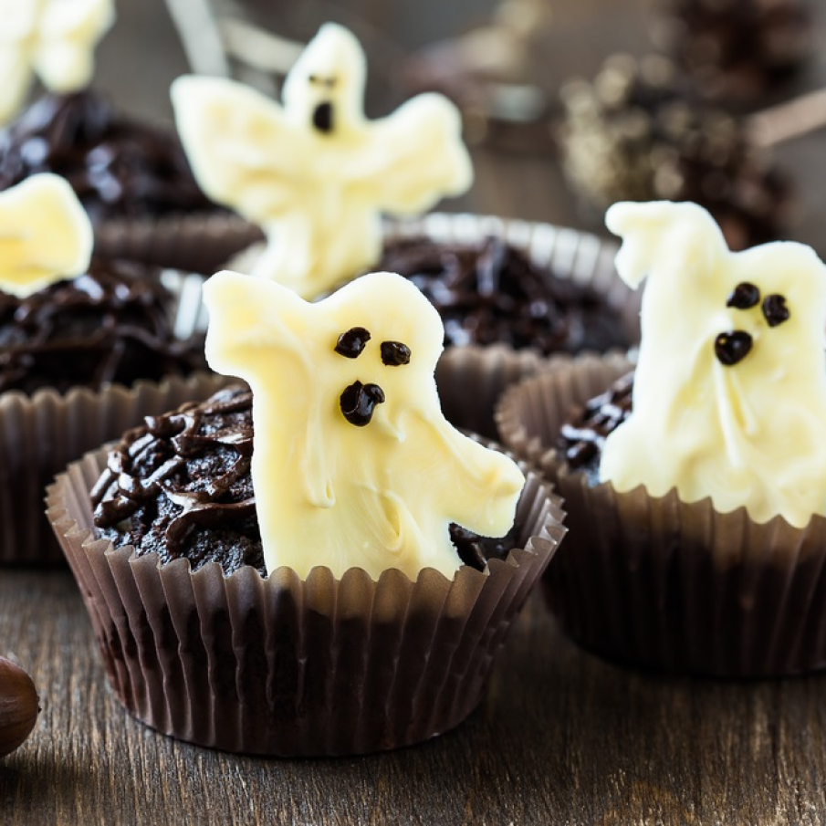 Muffins de ciocolată decorate cu fantomite înfricoșătoare din ciocolată albă cu ochișori negri 
