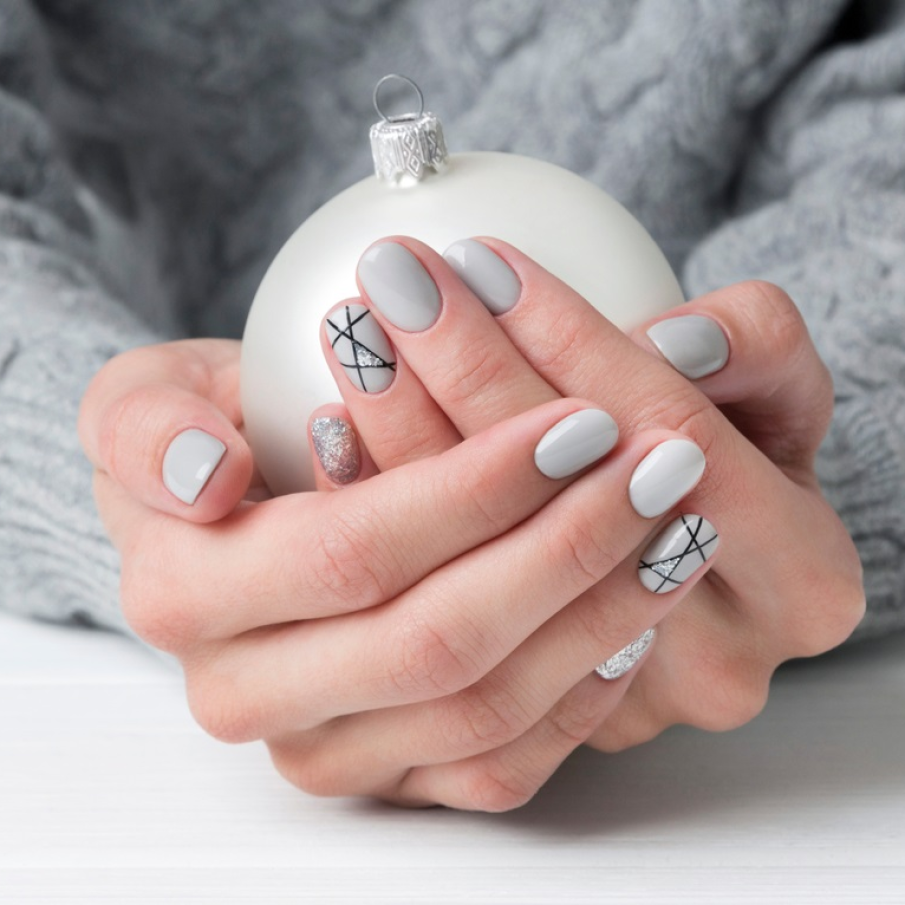 Manichiura de Craicun: dungi intersectate pe linia aratatorului, oja in nuanta de gri sau alb murdar asemenea zapezii si accente stralucitoare de glitter