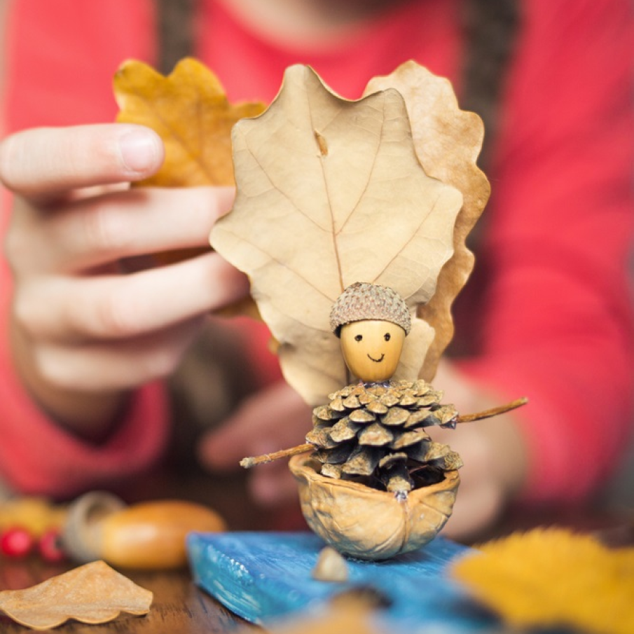 Barcă pe valuri realizată din frunze de toamnă și alte materiale naturale precum coji de nucă, con de brad, ghindă, bețe uscate