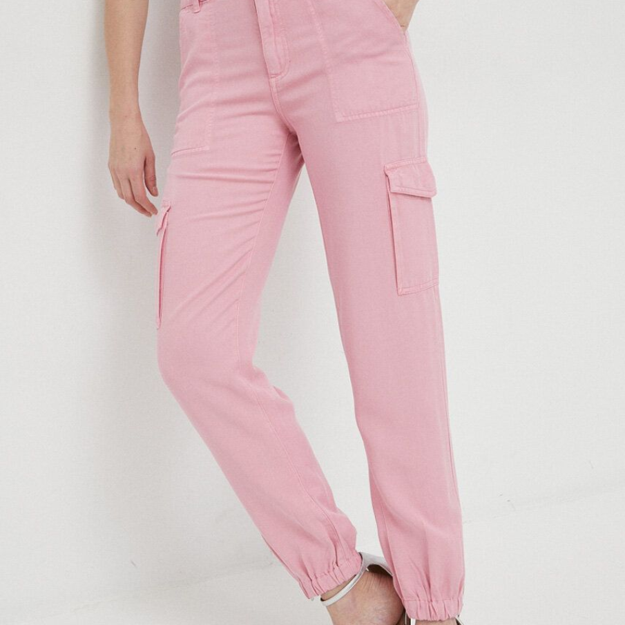 Pantaloni roz de la Guess, tip țigaretă, confecționați din material cu fibre TENCEL. Pantalonii au fost finisați în partea de jos cu manșete